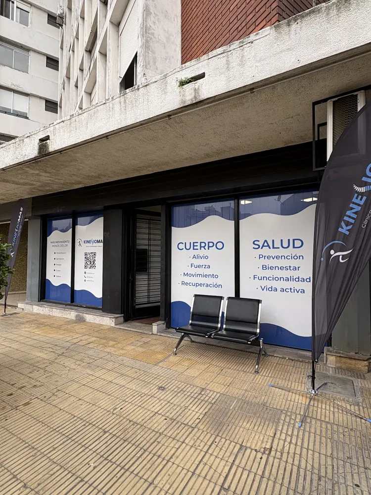 La fachada de Kinesiomas en La Paz 1209: vidriera azul con el logo y dos sillas en la entrada